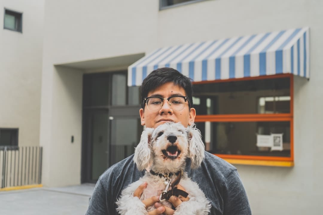 service dog questions — man in gray sweater holding white long coated dog